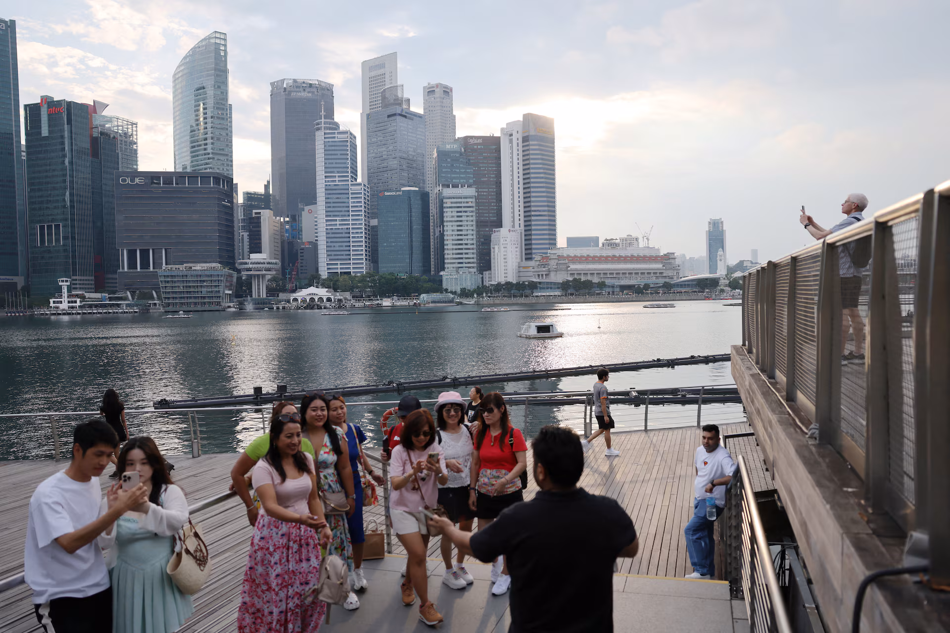 People take photos of the central business district skyline in Singapore
