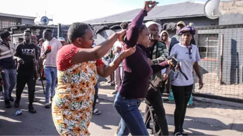 A woman, allegedly an undocumented migrant, is confronted as protesters search for foreign nationals during an anti-migrant march in Alexandra on 9 July 2026.