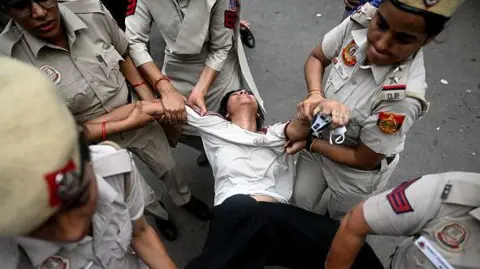 Getty Images olice personnel detain a supporter of the Cockroach Janta Party (CJP) during a protest demanding the resignation of India's Education Minister Dharmendra Pradhan over alleged NEET examination irregularities in New Delhi on July 20, 2026.