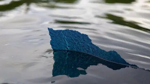 The Washington Post via Getty Images  A piece of the new blue paint with a ragged edge, is seen above the water