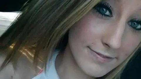 Aurora Police Department Chelsea Yasser smiles slightly at the camera, her blond hair falling to her chin and shoulders and her eyes made up with heavy mascara and liner