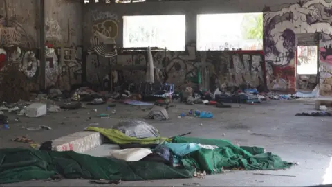Reuters The inside of a neglected warehouse. The walls are graffitied and rubbish is strewn on the concrete floor. Bright light streams in through the window. 
