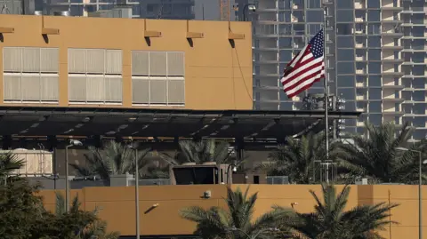 Getty Images The US flag flutters outside the US Embassy, seen across the Tigris River in Baghdad's fortified Green Zone in March 2026
