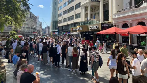 A long queue of cinemagoers at London's Leicester Square as they wait to enter the cinema.