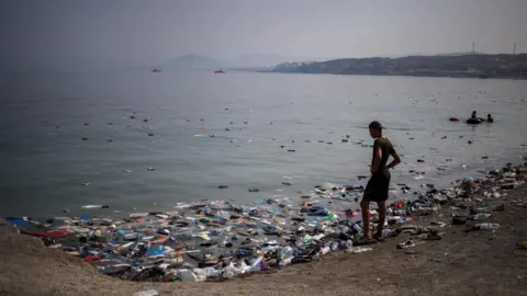 Reuters A migrant looks at the sneakers on the water following mass crossings of migrants on foot and by sea from Morocco into Spanish territory.