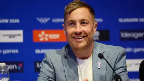 Getty Images Phil Batty smiling. He is in a blue jacket and white T-shirt and has blonde hair.
