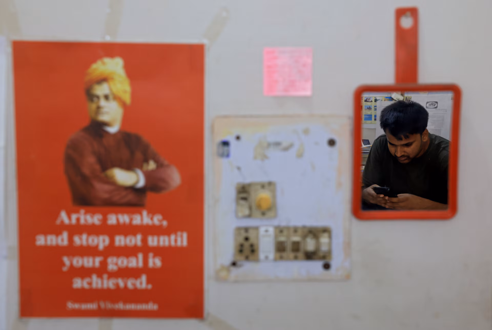 Ashok Kumar uses his mobile phone inside his one room rented flat in New Delhi