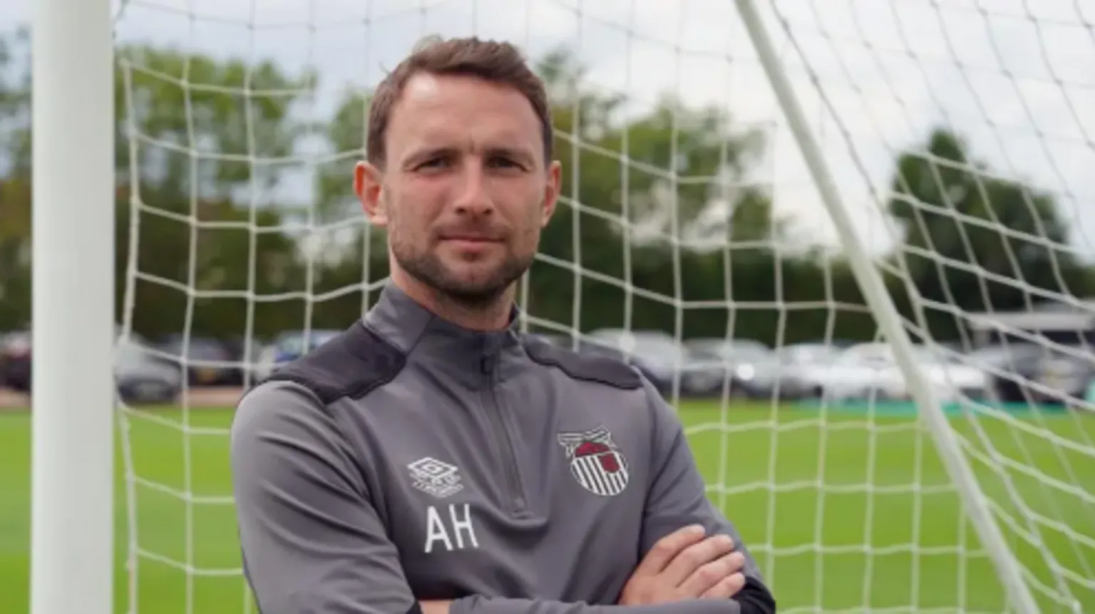 Grimsby Town Image shows Alex Hughes, 37, wearing his grey Grimsby Town training top and standing in front of a set of goals.